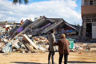 A man and woman look at a collapsed building in Islahyia, Türkiye, on 7 February 2023. The use of photos must be factual, and should be used in the same context as described in the caption.