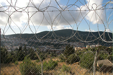 Barbed wire fence surrounding the mobile migrant reception centre on the Greek island of Samos. In December 2014 the Ministry of Health of Greece through the Hellenic Center for Disease Control and Prevention and WHO/Europe conducted a joint assessment of the country's capacity to cope with the public health challenges of migration from a health system perspective. 

The identification procedure takes place in a mobile reception centre located on Samos, which has capacity for 285 migrants. In the summer overcapacity is a problem. In September 2014, about 900 migrants were living in the centre, some of them staying temporarily in tents outside the facilities.