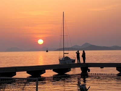 Two people walking on a dock as the sun sets in Dubrovnik.