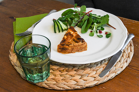 A plate with quiche or similar and accompanying salad, along with a drink.