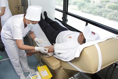A health worker prepares to insert a needle into a blood donor's arm for blood donation during a World Blood Donor Day campaign, 2014.